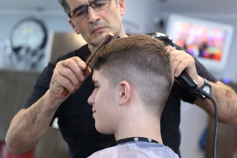 fryzjer modelujący włosy klientowi