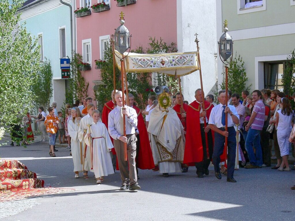 Procesja Bożego Ciała w Austrii – wierni uczestniczą w tradycyjnych obchodach z chorągwiami i dekoracjami kwiatowymi.